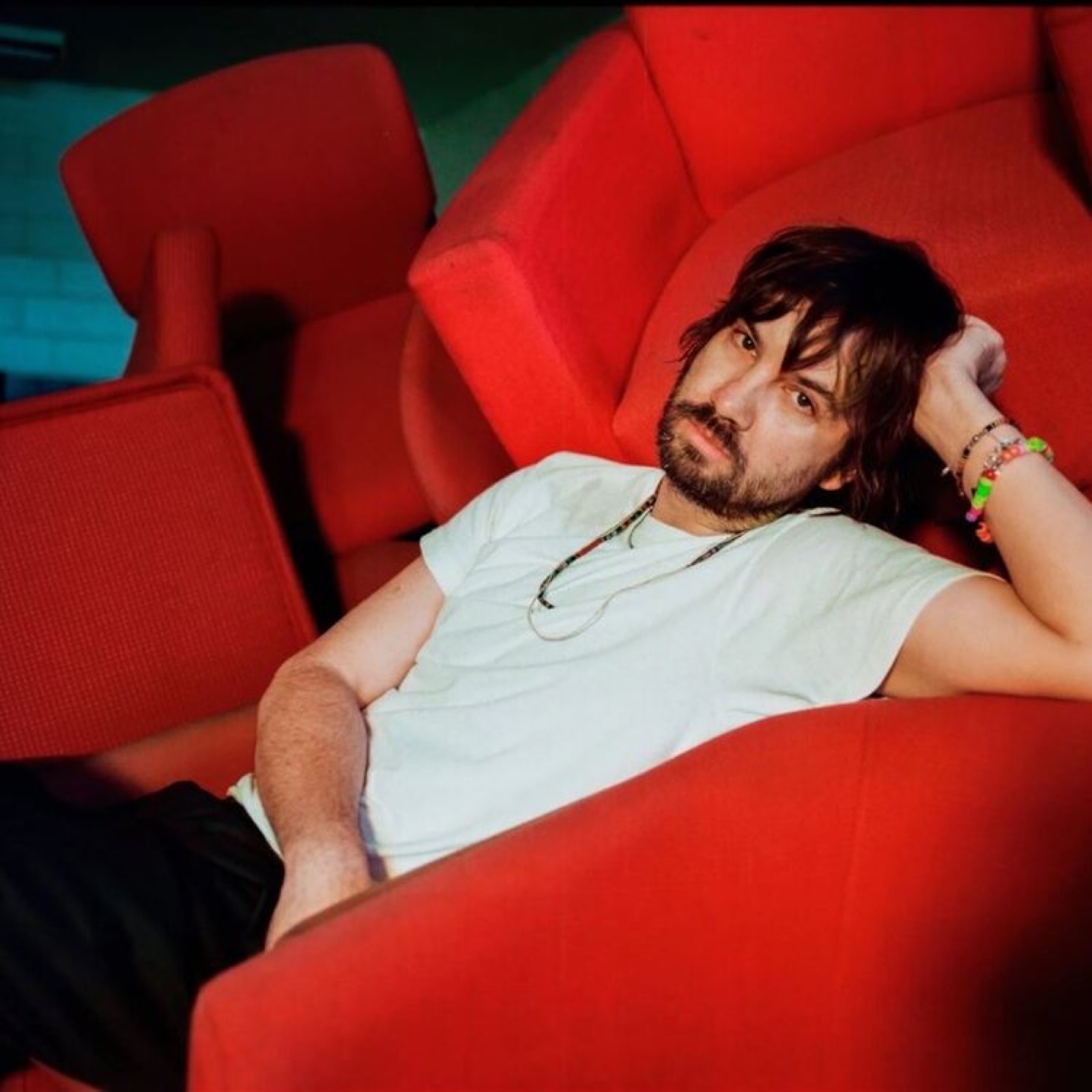 Kevin Parker of Tame Impala reclining in a contemporary promotional portrait.